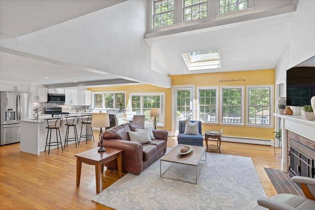 1 Emerson Dr, Acton, MA 01720 - living area with a baseboard heating unit, a high ceiling, light wood finished floors, a fireplace with flush hearth, and a skylight
