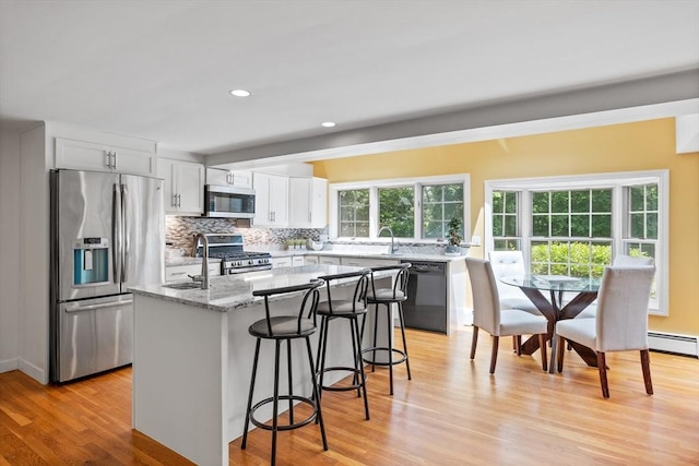 1 Emerson Dr, Acton, MA 01720 - kitchen featuring stainless steel appliances, a center island, light wood-style floors, backsplash, and white cabinets