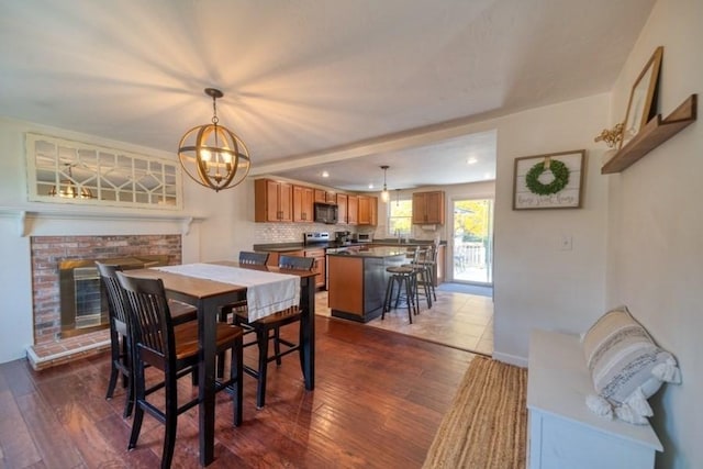 dining space featuring a notable chandelier, a fireplace, and dark hardwood / wood-style flooring