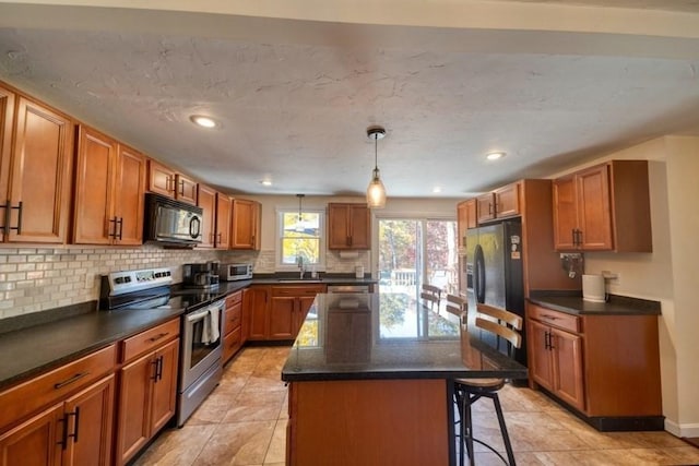 kitchen with sink, decorative light fixtures, a kitchen breakfast bar, a kitchen island, and black appliances