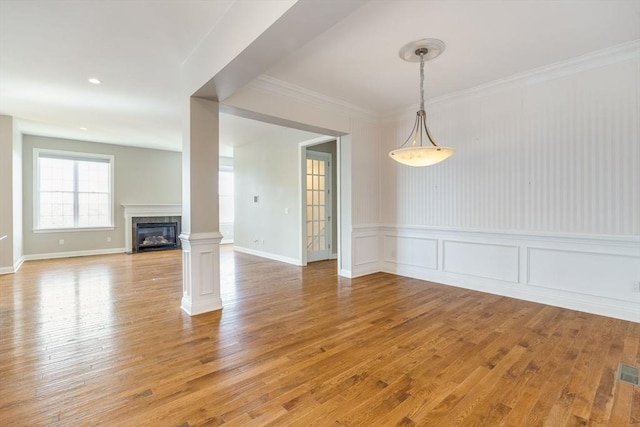 12 Skipping Stone, Plymouth, MA 02360 - unfurnished dining area with light wood-type flooring, a premium fireplace, ornamental molding, a decorative wall, and wainscoting