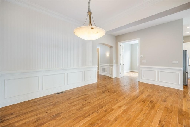 12 Skipping Stone, Plymouth, MA 02360 - unfurnished dining area featuring arched walkways, light wood-style floors, a decorative wall, crown molding, and a wainscoted wall