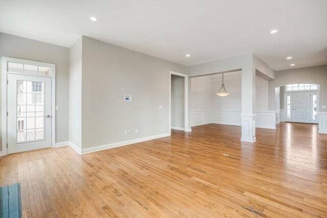 12 Skipping Stone, Plymouth, MA 02360 - unfurnished living room with light wood finished floors, ornate columns, a wainscoted wall, recessed lighting, and a decorative wall