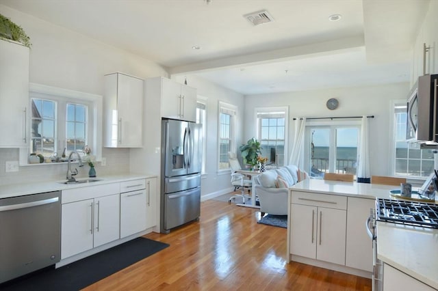 148 Winthrop Shore Dr Unit 5, Winthrop, MA 02152 - kitchen with appliances with stainless steel finishes, light wood finished floors, white cabinetry, light countertops, and backsplash