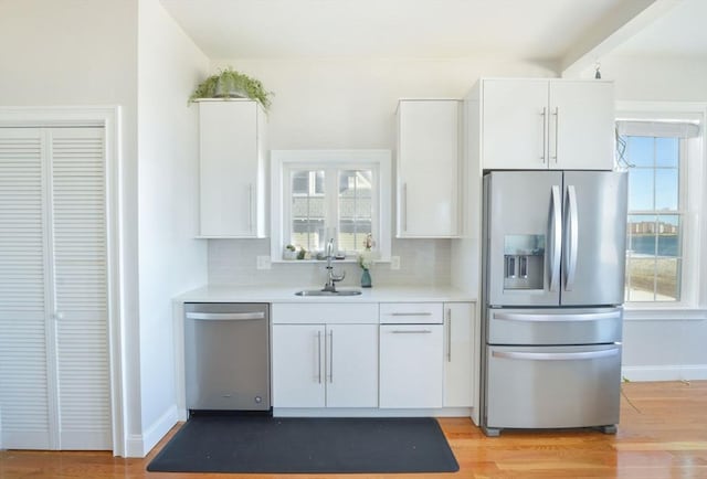 148 Winthrop Shore Dr Unit 5, Winthrop, MA 02152 - kitchen featuring appliances with stainless steel finishes, decorative backsplash, light countertops, white cabinets, and light wood-type flooring