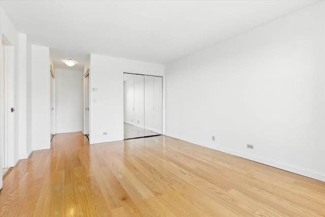 unfurnished bedroom featuring baseboards, a closet, and light wood-type flooring