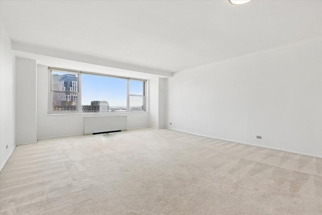 spare room with baseboards, carpet, and radiator