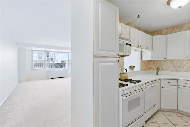 kitchen featuring white appliances, white cabinetry, a sink, and light countertops