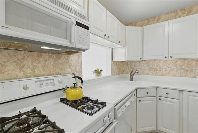kitchen with white cabinets, a sink, white appliances, light countertops, and backsplash