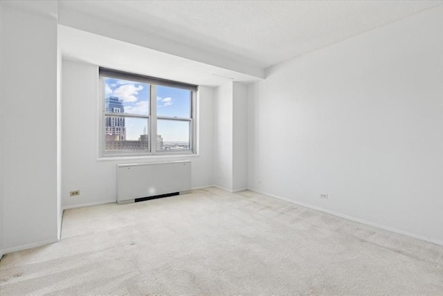 carpeted spare room with radiator and baseboards