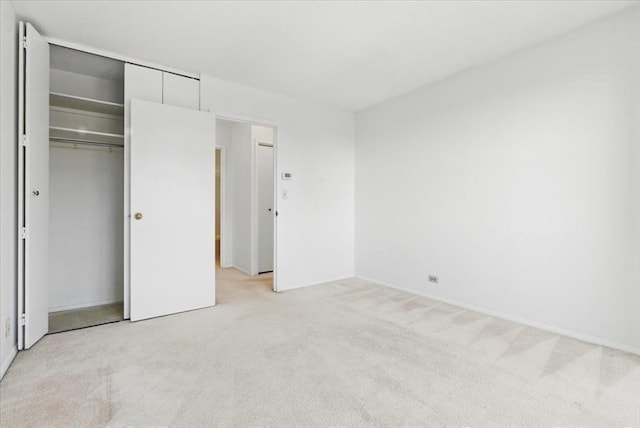unfurnished bedroom with a closet and light carpet