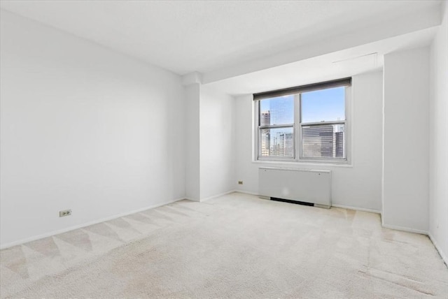 unfurnished room featuring light colored carpet, radiator, and baseboards