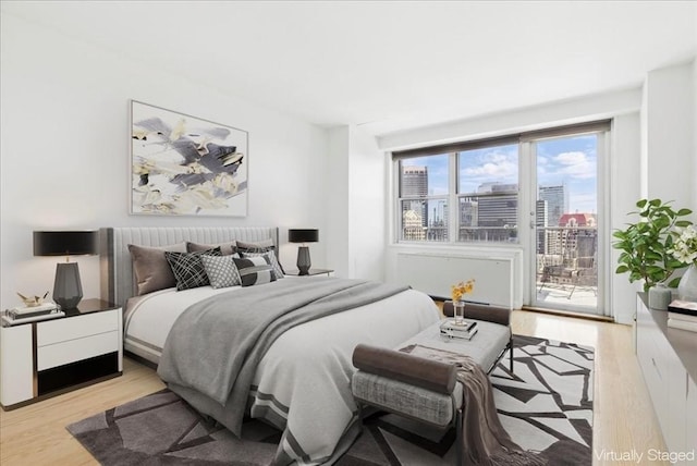 bedroom with access to outside, a city view, and light wood-type flooring