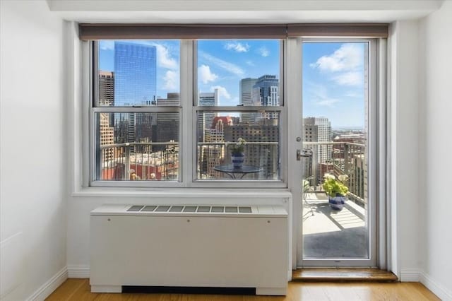 doorway to outside featuring a healthy amount of sunlight, radiator, and a city view