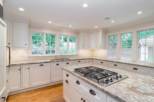 617 S St, Needham, MA 02492 - kitchen with stainless steel gas cooktop, a sink, white cabinets, light wood-type flooring, and ornamental molding