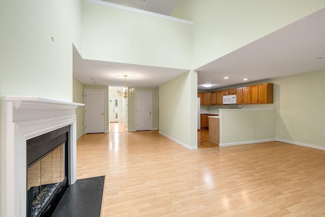 15 Pebble Bch Unit 2005-103, Mashpee, MA 02649 - unfurnished living room featuring a chandelier, light wood-style floors, a glass covered fireplace, a towering ceiling, and recessed lighting