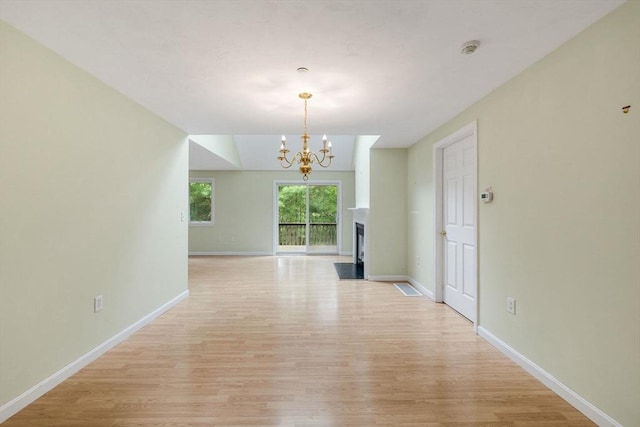 15 Pebble Bch Unit 2005-103, Mashpee, MA 02649 - unfurnished living room with light wood-type flooring, a chandelier, and a fireplace