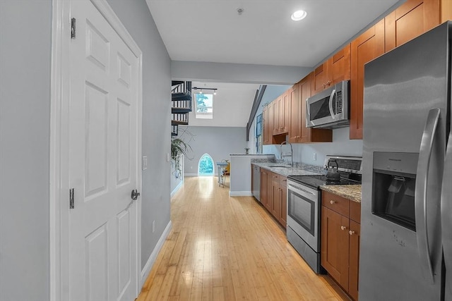 28 Broad St Unit 203, Marlborough, MA 01752 - kitchen with stainless steel appliances, brown cabinets, light wood-style floors, and light stone counters