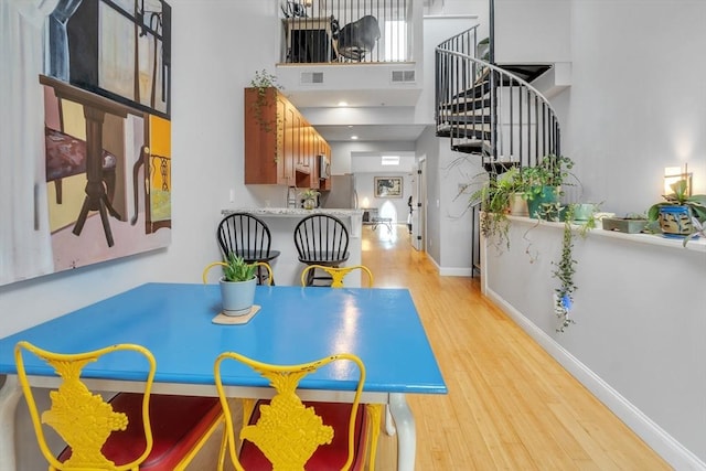 28 Broad St Unit 203, Marlborough, MA 01752 - dining area with stairs, light wood finished floors, and a towering ceiling
