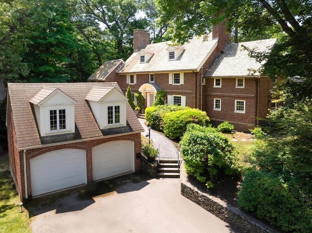 86 Waban Ave, Newton, MA 02468 - view of front of house featuring a chimney, brick siding, a garage, and asphalt driveway