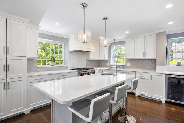 86 Waban Ave, Newton, MA 02468 - kitchen featuring wine cooler, ornamental molding, light countertops, custom exhaust hood, and white cabinets