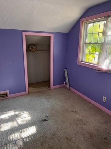 unfurnished bedroom featuring carpet flooring, a closet, and lofted ceiling