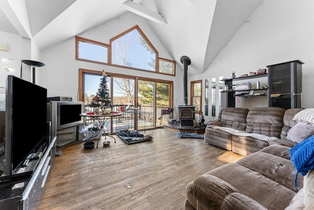 living room with wood-type flooring, a wood stove, and high vaulted ceiling