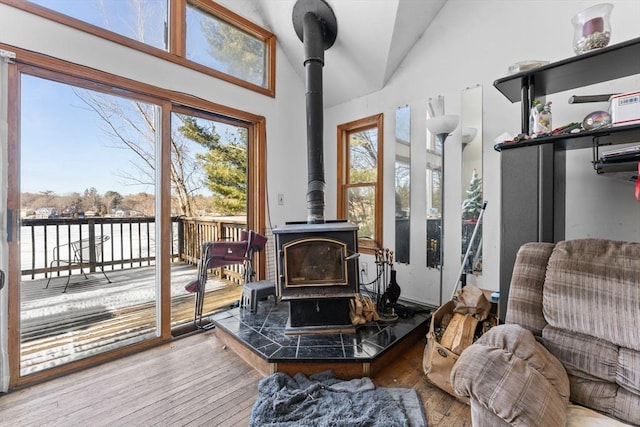 sitting room with lofted ceiling, light wood-type flooring, and a wood stove