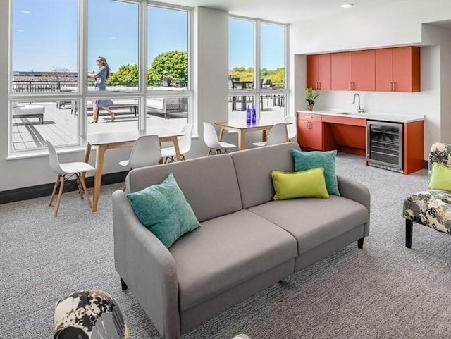 living room featuring a wealth of natural light, light colored carpet, beverage cooler, and sink