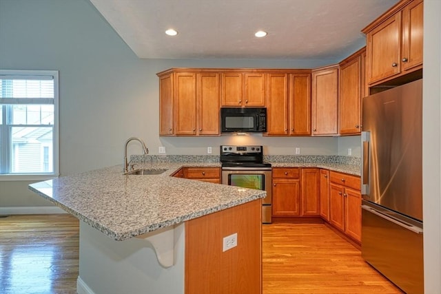 39 Balancing Rock Dr Unit 39, Holliston, MA 01746 - kitchen with stainless steel appliances, a peninsula, brown cabinetry, a kitchen breakfast bar, and light wood-style flooring