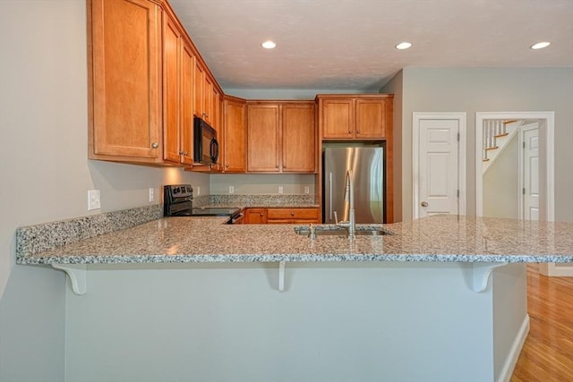 39 Balancing Rock Dr Unit 39, Holliston, MA 01746 - kitchen featuring black appliances, a breakfast bar area, a peninsula, light wood-style floors, and recessed lighting