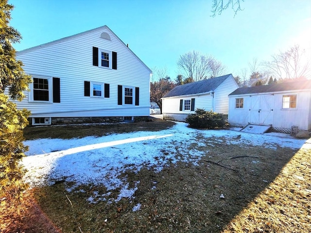 snow covered property with an outbuilding