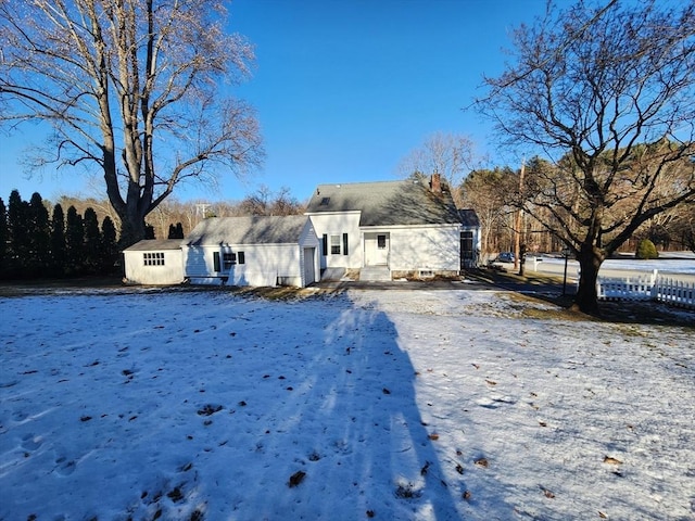 snow covered rear of property with a storage unit