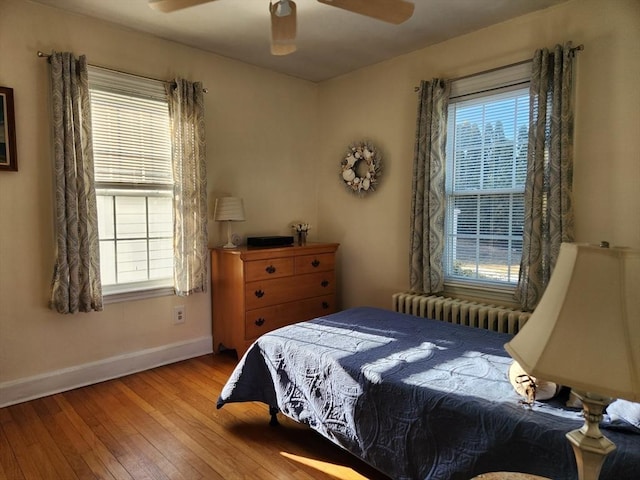 bedroom featuring light hardwood / wood-style flooring, radiator heating unit, and ceiling fan