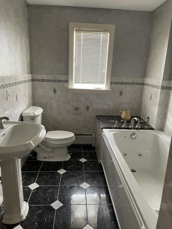 full bath with wainscoting, toilet, a whirlpool tub, a baseboard heating unit, and tile walls