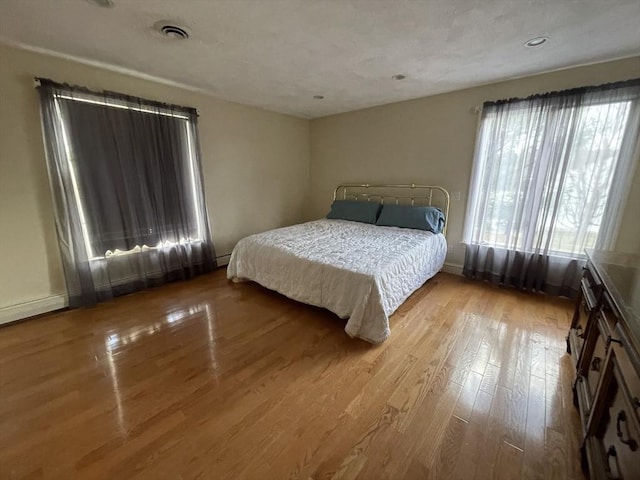 bedroom with multiple windows, visible vents, and wood finished floors