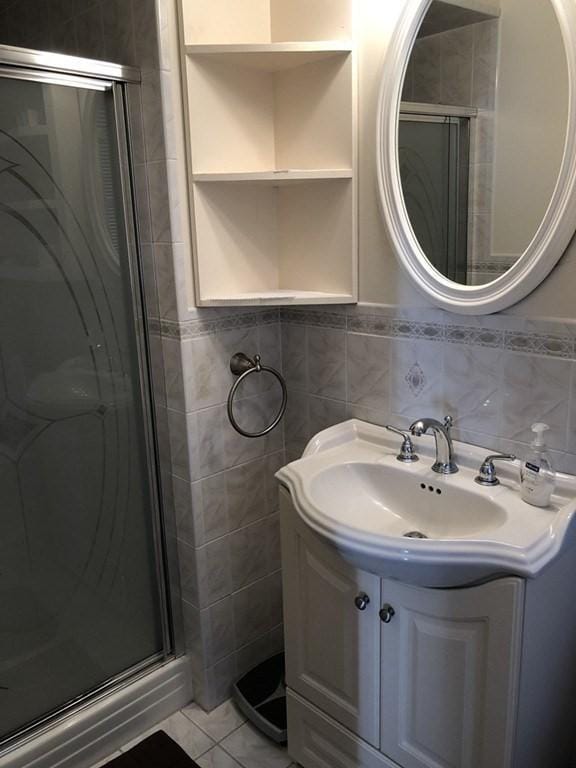 full bath with a shower stall, tile walls, and vanity