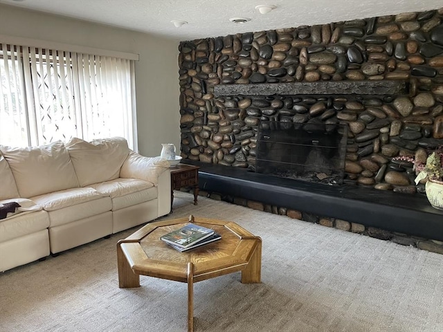 living room featuring carpet floors, a textured ceiling, and a stone fireplace