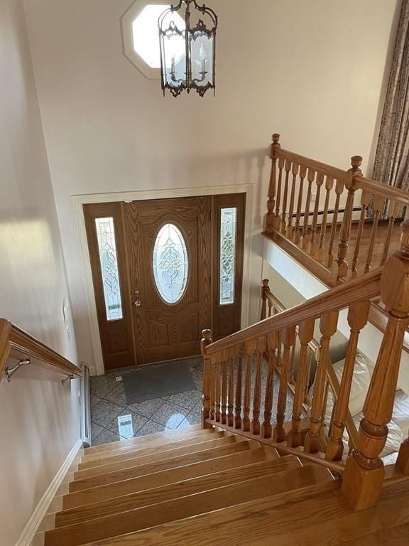 entrance foyer with a chandelier, a high ceiling, stairway, and granite finish floor