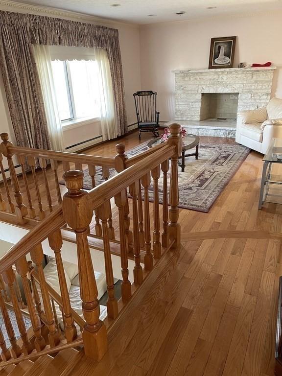 sitting room with light wood-type flooring, a fireplace with raised hearth, and a baseboard radiator