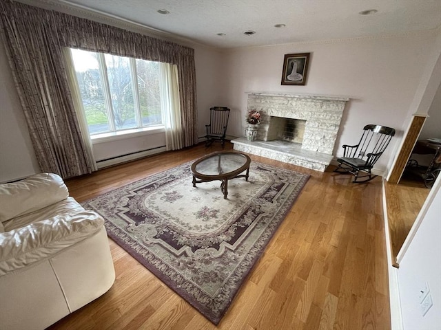 living area with baseboard heating, wood finished floors, and a stone fireplace