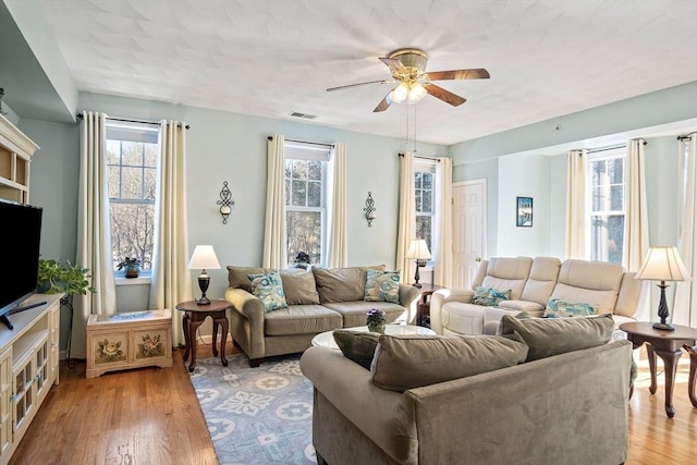 living room with ceiling fan, plenty of natural light, and light hardwood / wood-style floors