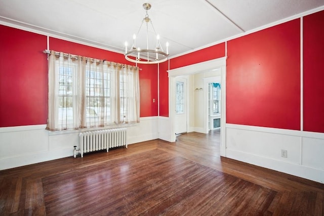 unfurnished dining area with wood-type flooring, a chandelier, radiator, and ornamental molding