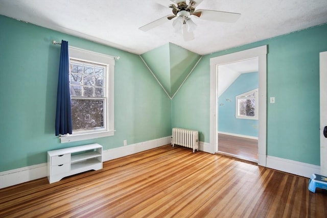 bonus room featuring ceiling fan, wood-type flooring, radiator heating unit, and vaulted ceiling