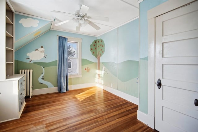 interior space with radiator heating unit, vaulted ceiling, ceiling fan, built in shelves, and hardwood / wood-style floors