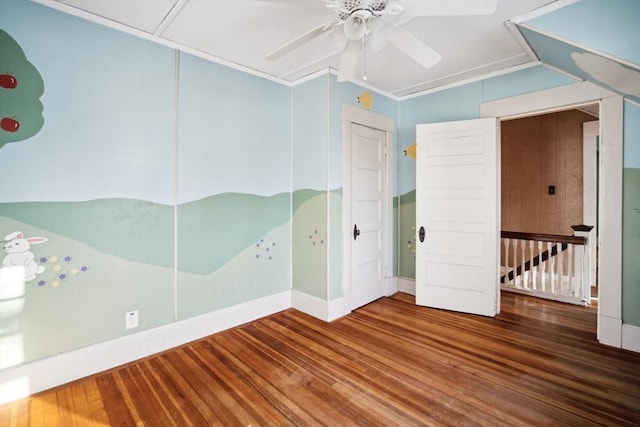 unfurnished bedroom featuring hardwood / wood-style flooring, a closet, a nursery area, ornamental molding, and ceiling fan