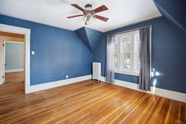 additional living space featuring hardwood / wood-style flooring, radiator, lofted ceiling, and ceiling fan