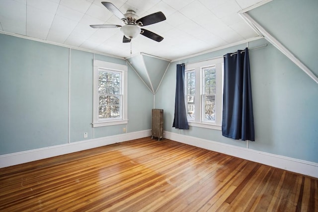 additional living space with radiator heating unit, hardwood / wood-style flooring, and ceiling fan