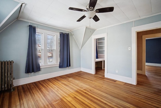 additional living space with ceiling fan, radiator, and hardwood / wood-style floors