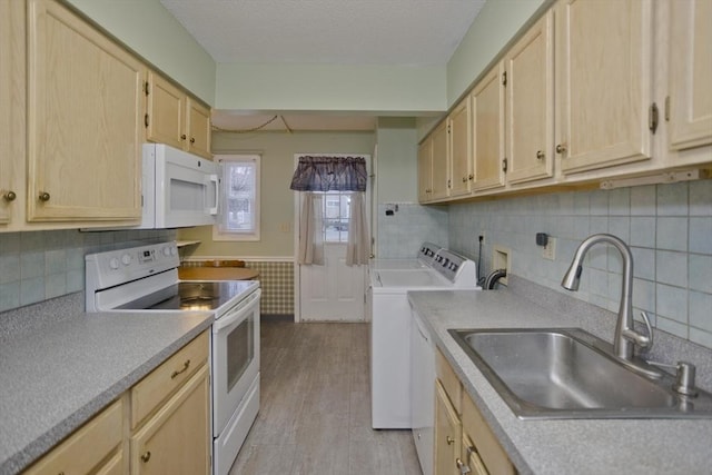 kitchen featuring sink, light brown cabinets, separate washer and dryer, light hardwood / wood-style floors, and white appliances